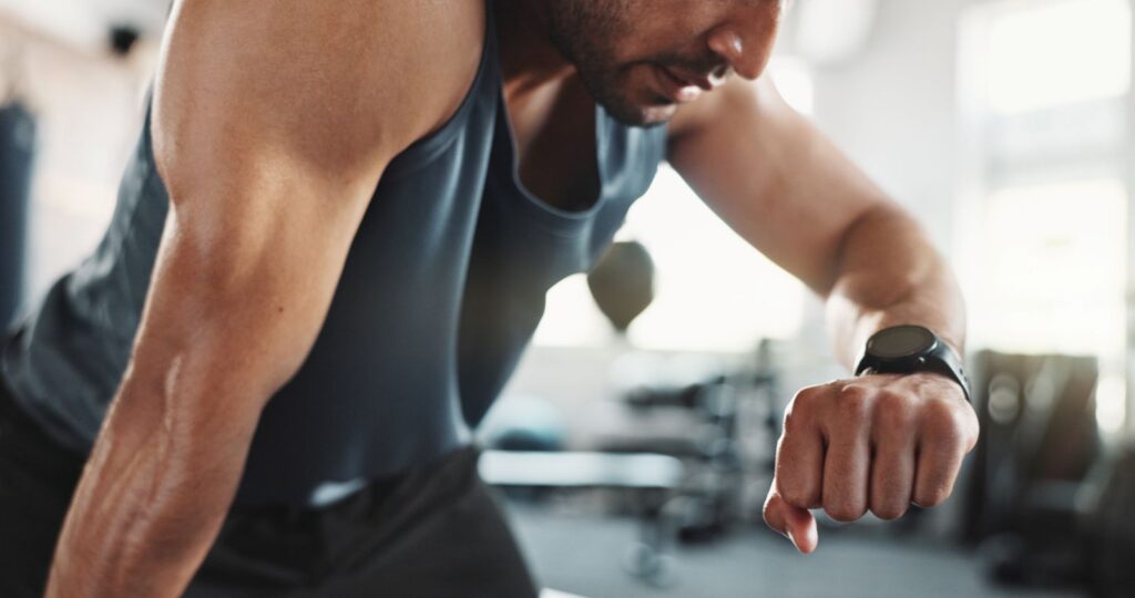 Homem numa academia monitorando treino para avaliar 1 hora de musculação queima quantas calorias​.