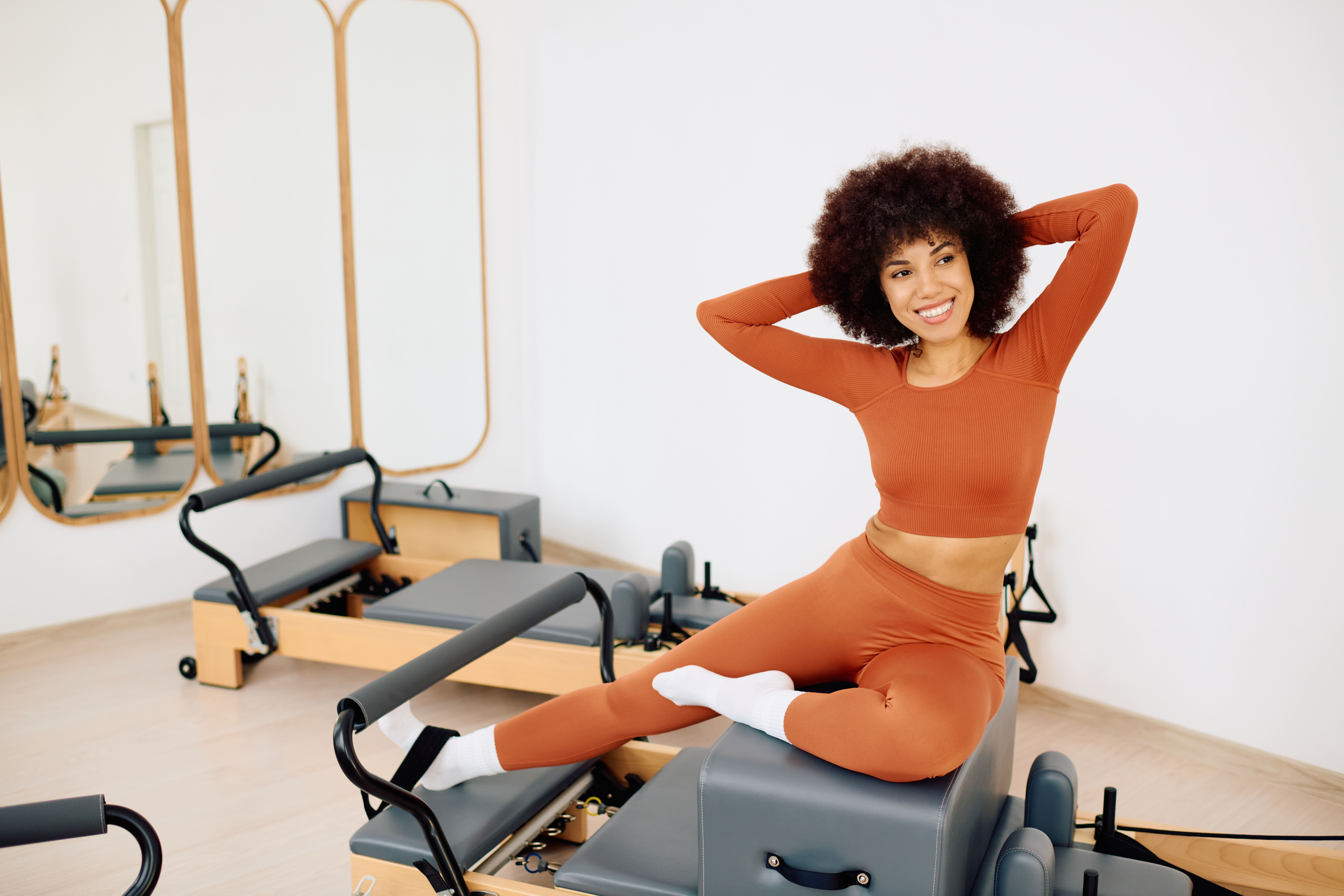 Mulher praticando Pilates em aparelho reformer em estúdio moderno, destacando força, alongamento e postura.