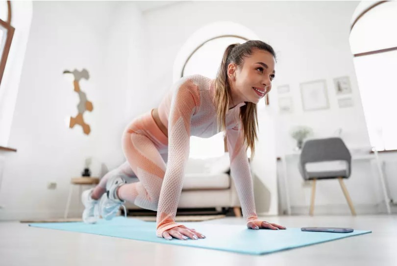 Mulher praticando abdominal alpinista no chão da sala.