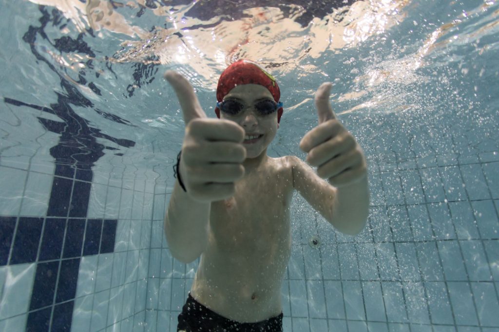 A natação infantojuvenil pode ser a escolha ideal entre as atividades físicas quando o assunto é o desenvolvimento do seu filho! 
Realizar atividades dentro da piscina é uma maneira bastante funcional para integrar, envolver e ensinar uma cultura de autocuidado e sociabilidade aos jovens. 
Neste conteúdo, saiba quais são os benefícios de apostar em modalidades como a aula de natação infantojuvenil.
