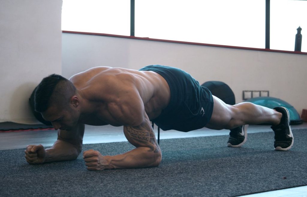 homem sem camisa realiza exercicio de prancha, ideal para os músculos do core