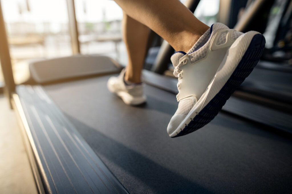 Pessoa correndo em uma esteira ergométrica na academia, destacando a prática diária de exercícios cardiovasculares para melhorar o condicionamento físico, aumentar o gasto calórico e favorecer o emagrecimento.