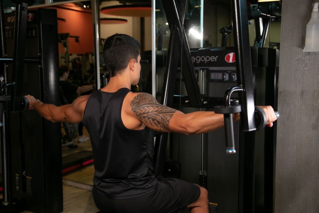 homem musculoso de costar realizando crucifixo como exercicio dorsal