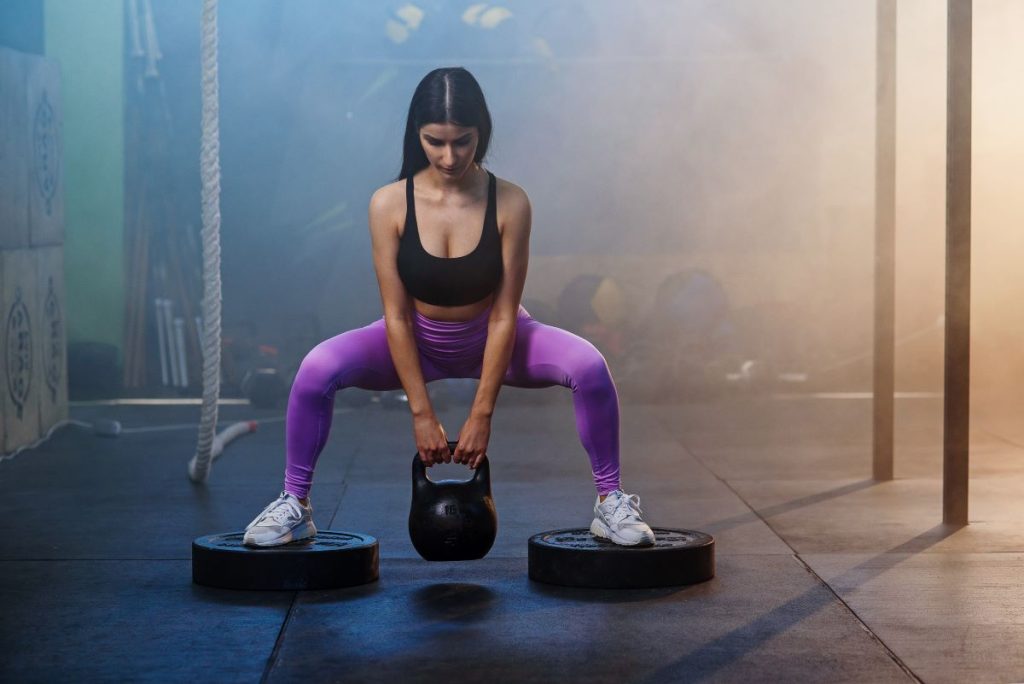 Aluna fazendo agachamento, exercicio para gluteo e pernas