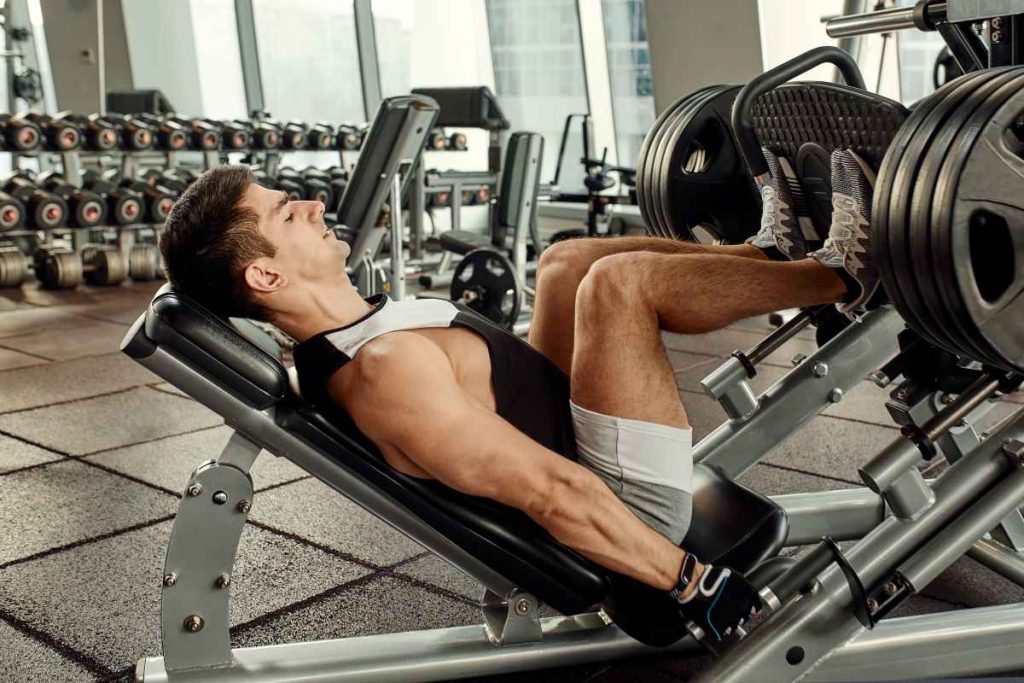 homem realizando o exercício leg press em uma academia.