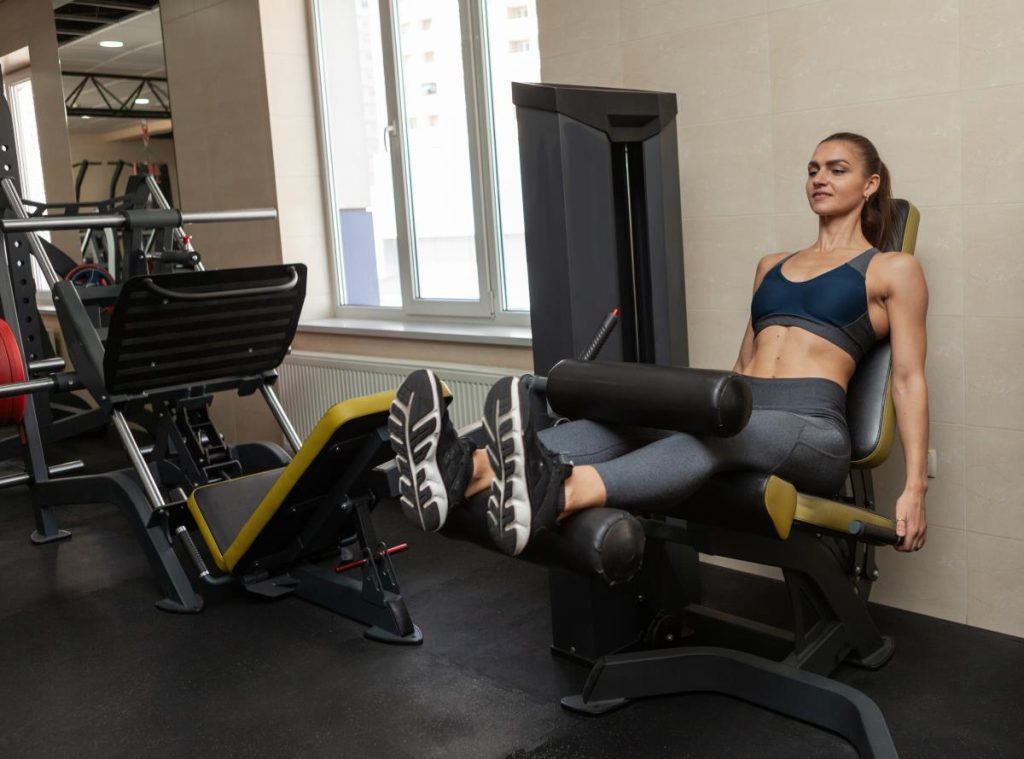 mulher realizando um exercício na cadeira flexora, com ênfase na musculatura posterior da coxa