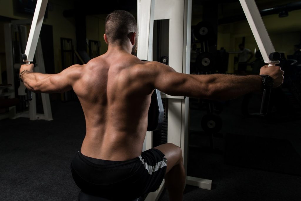  homem realizando um treino de costas em uma máquina de musculação.