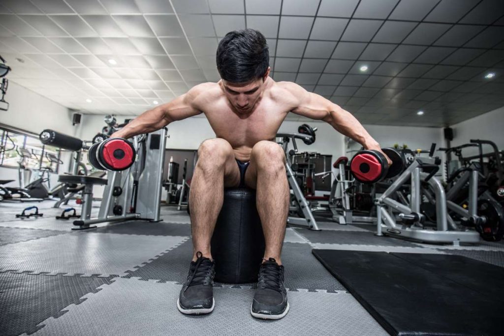 homem realizando o exercício de crucifixo invertido em uma academia.