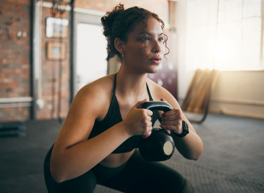 Mulher treinando força muscular com kettlebell.
