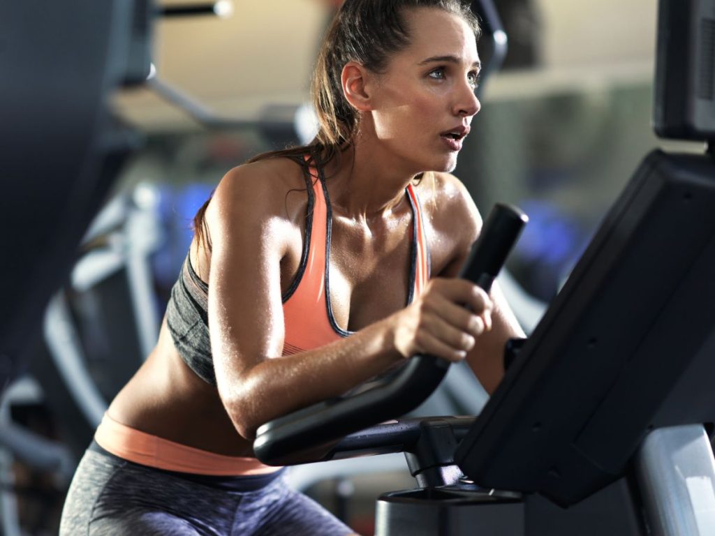 Mulher fazendo aula de spinning como forma de treino que emagrece.