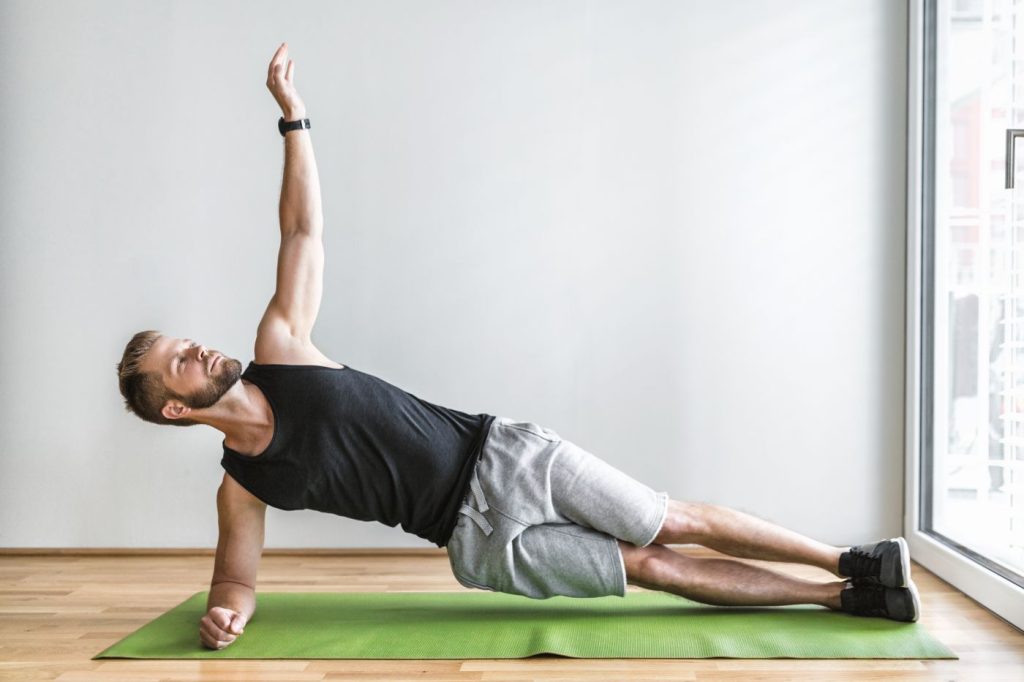 Homem realiza prancha lateral como exercícios para core.